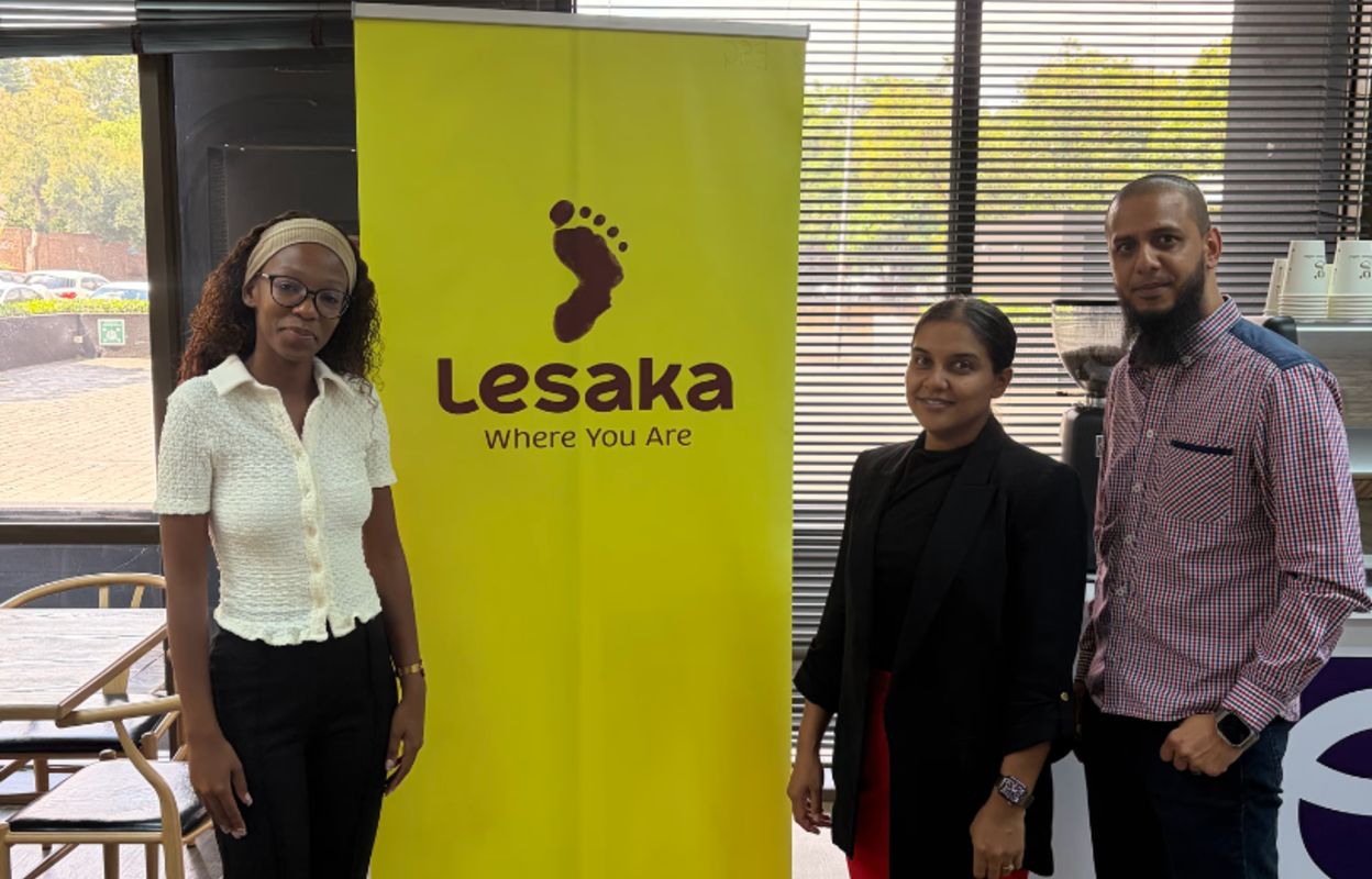 Greendot Café team standing in front of the Lesaka branding wall.