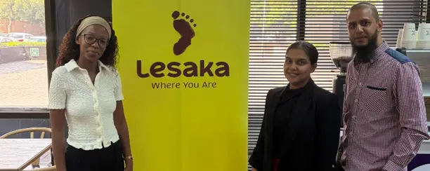 Greendot Café team standing in front of the Lesaka branding wall.
