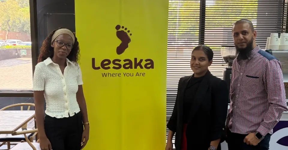 Greendot Café team standing in front of the Lesaka branding wall.