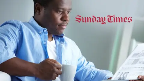 Man with coffee reading a newspaper