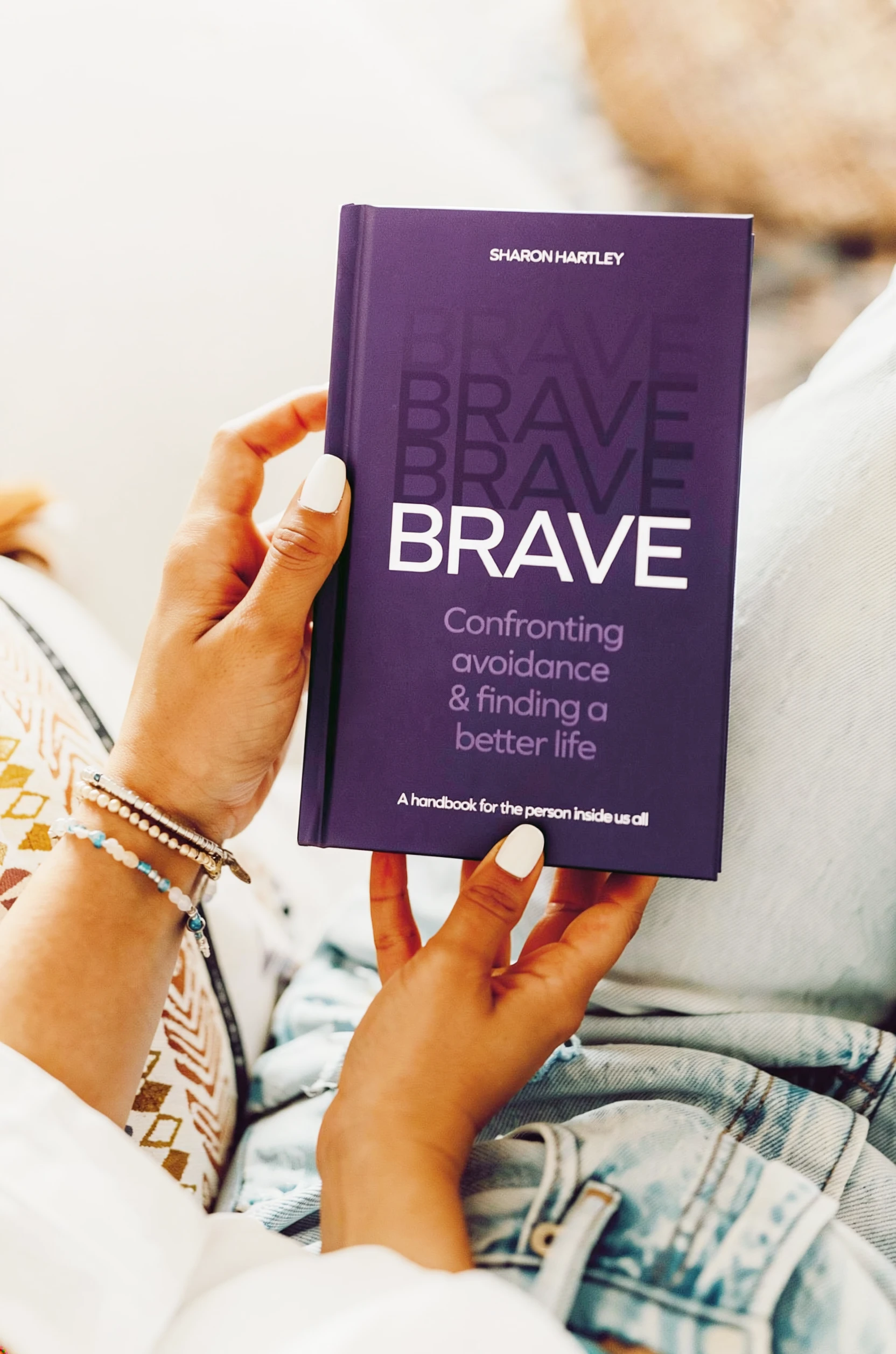 A woman looks at the front cover of Brave by Sharon Hartley