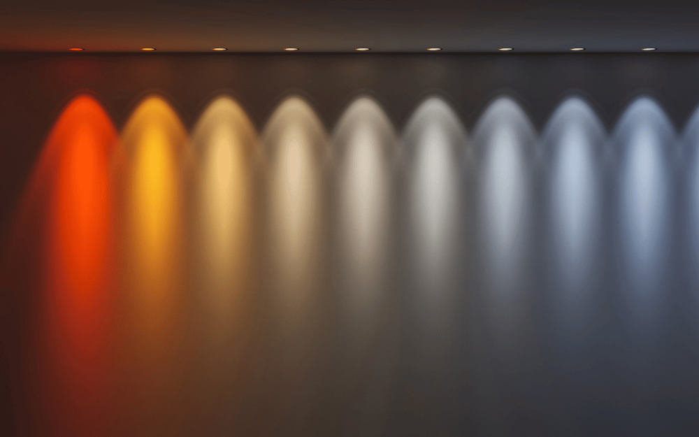 Row of downlights projecting a colour temperature scale on a wall, from warm amber through neutral to cool blue-white