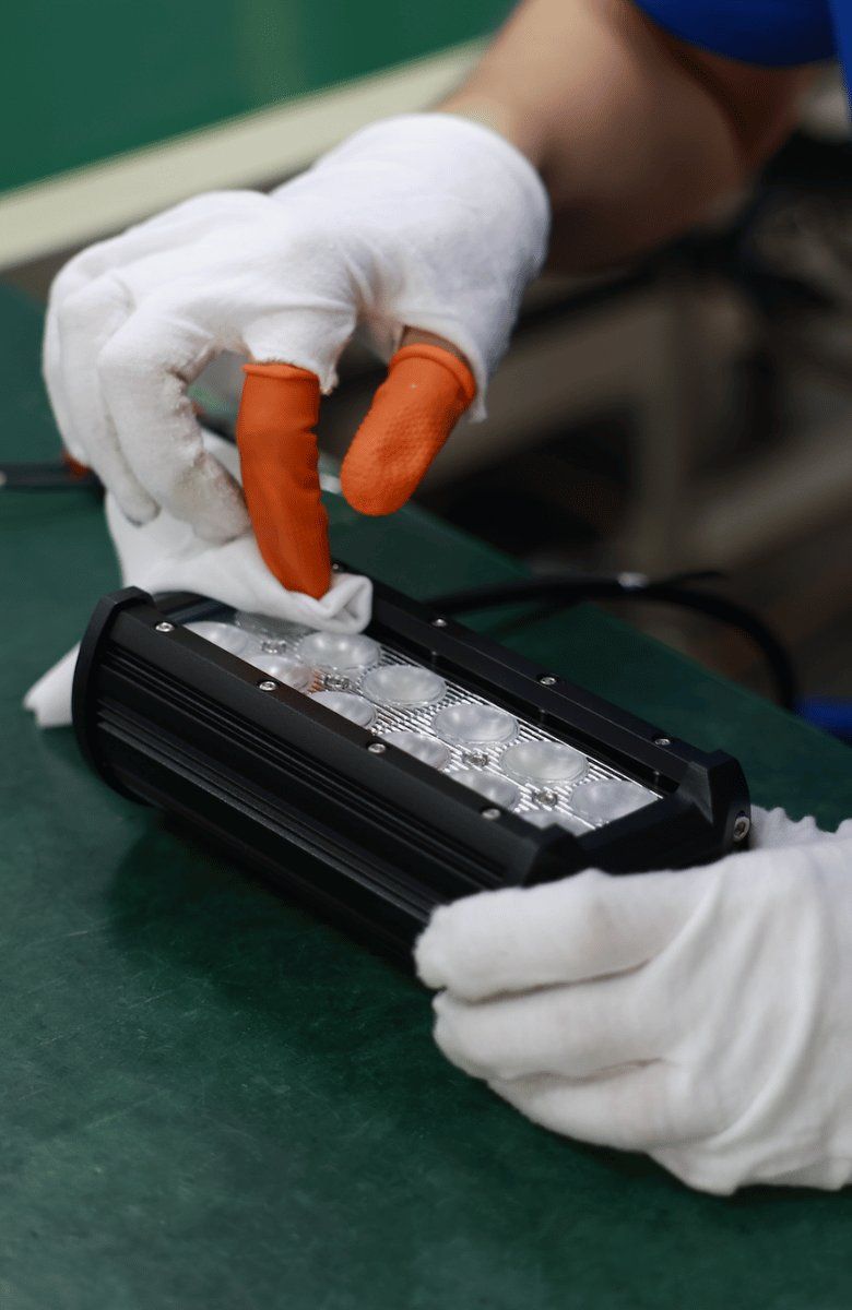 Final inspection and cleaning of an LED light bar with gloves at the Tough Lighting factory