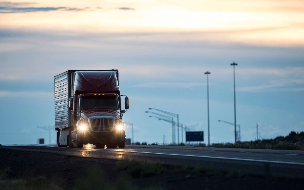 Truck driving on a highway at dusk with LED headlights and amber marker lights switched on
