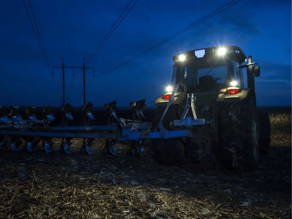 Tractor working at dusk with cab roof work lights and rear lamps lit