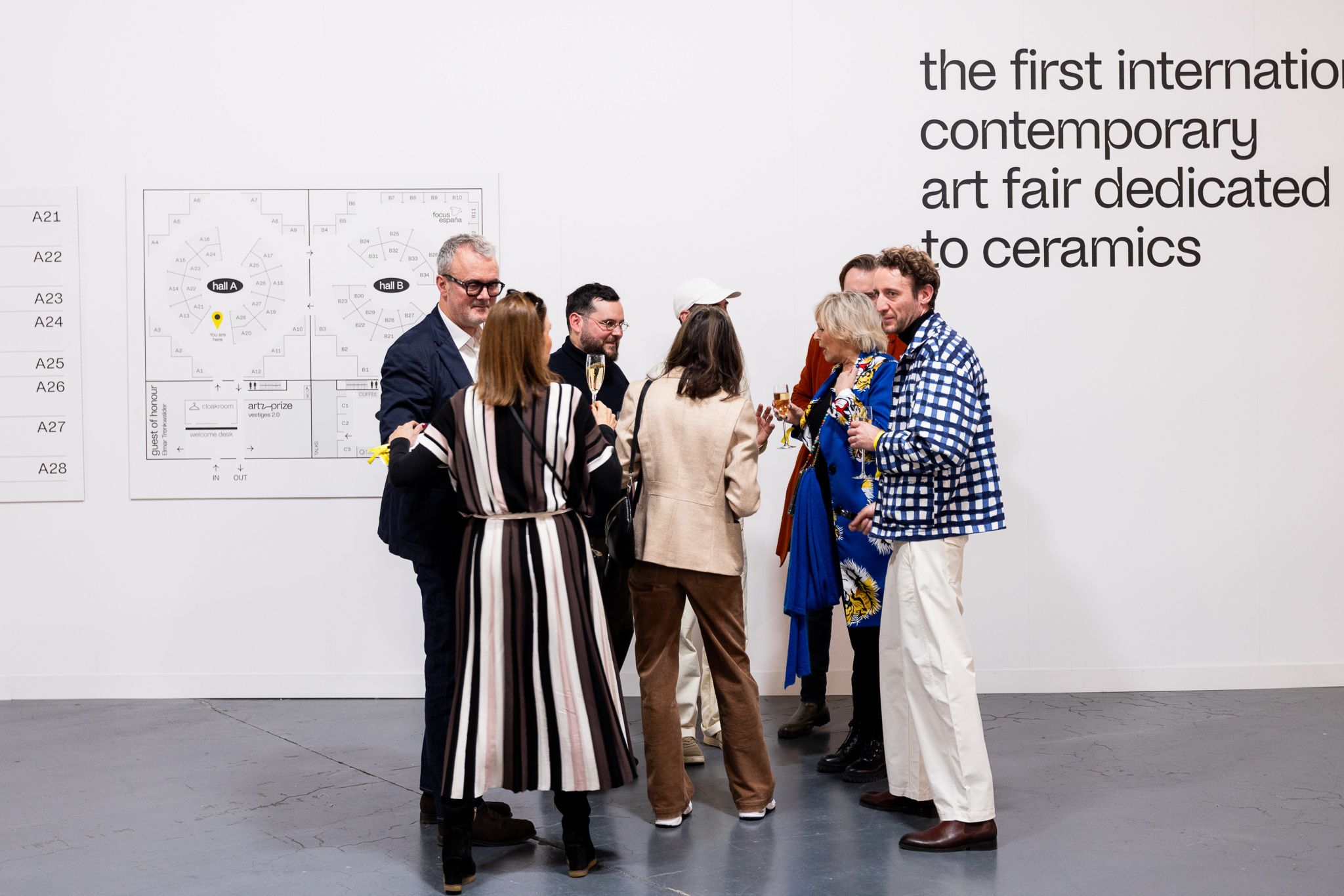 Visitors in conversation in front of the ceramic brussels entrance wall.