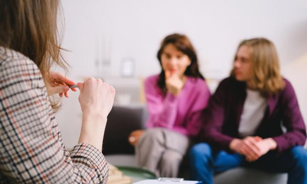 Psycholożka z notatnikiem i para siedząca naprzeciwko niej podczas pierwszej konsultacji