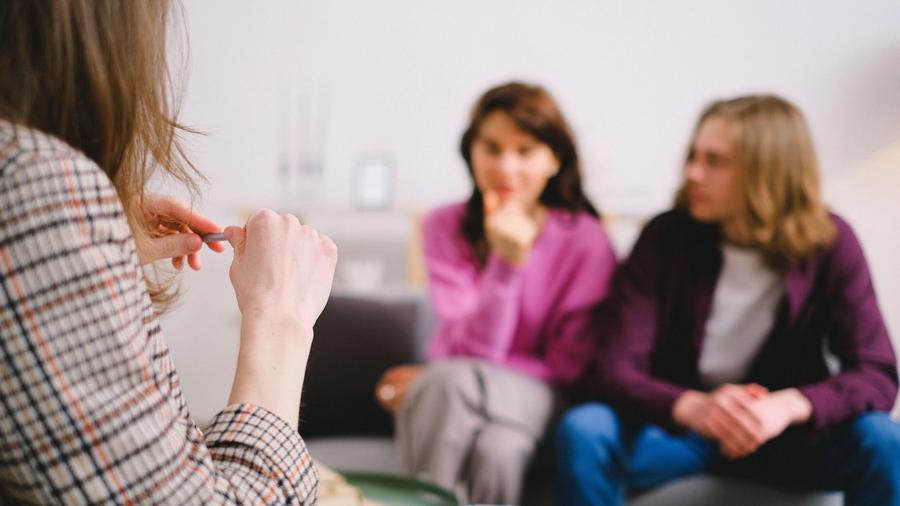 Psycholożka z notatnikiem i para siedząca naprzeciwko niej podczas pierwszej konsultacji