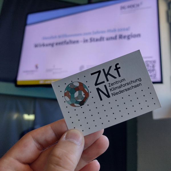 ZKfN business card in front of the conference screen at the DG HochN annual conference.