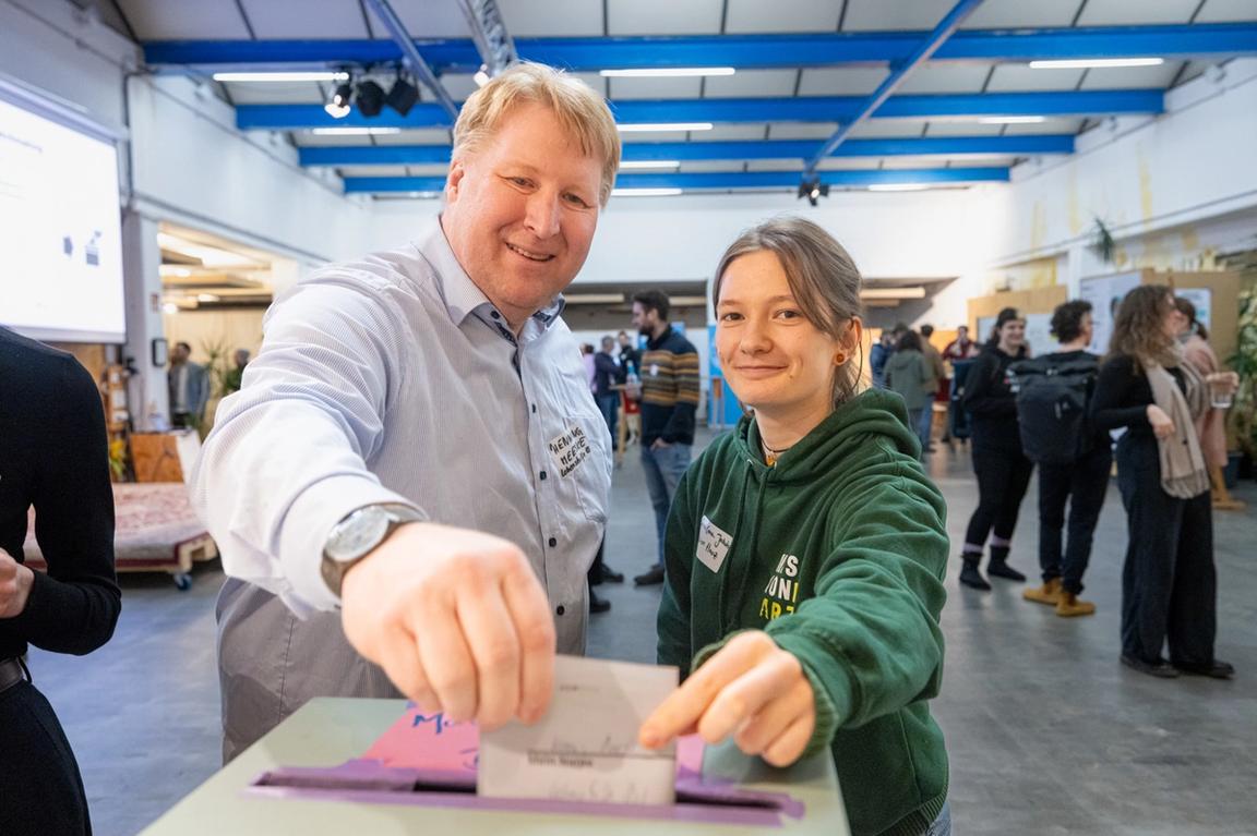 Zwei Teilnehmende stecken ihren Matchingzettel in die Matchingbox.