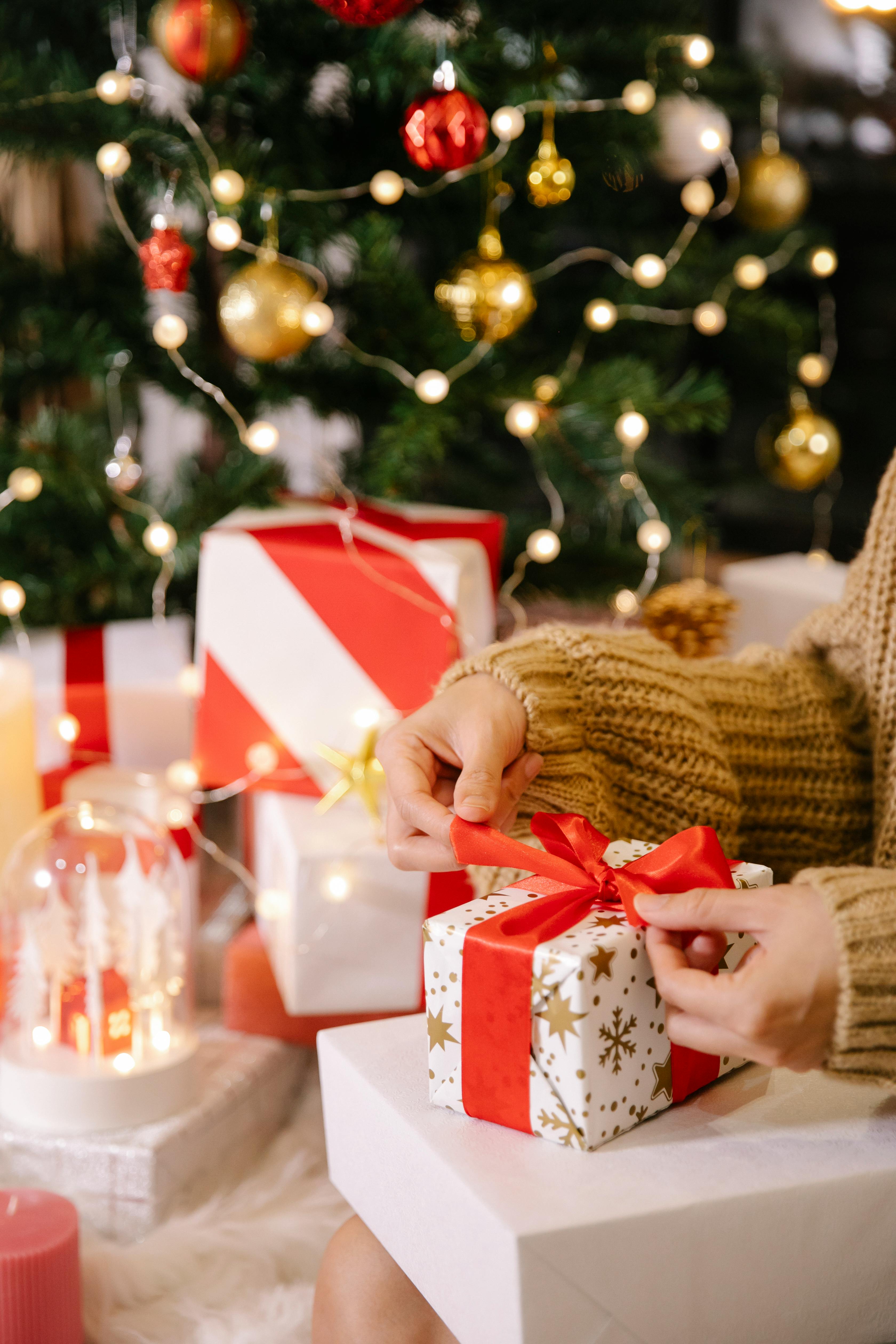 Woman preparing Christmas presents near decorated tree