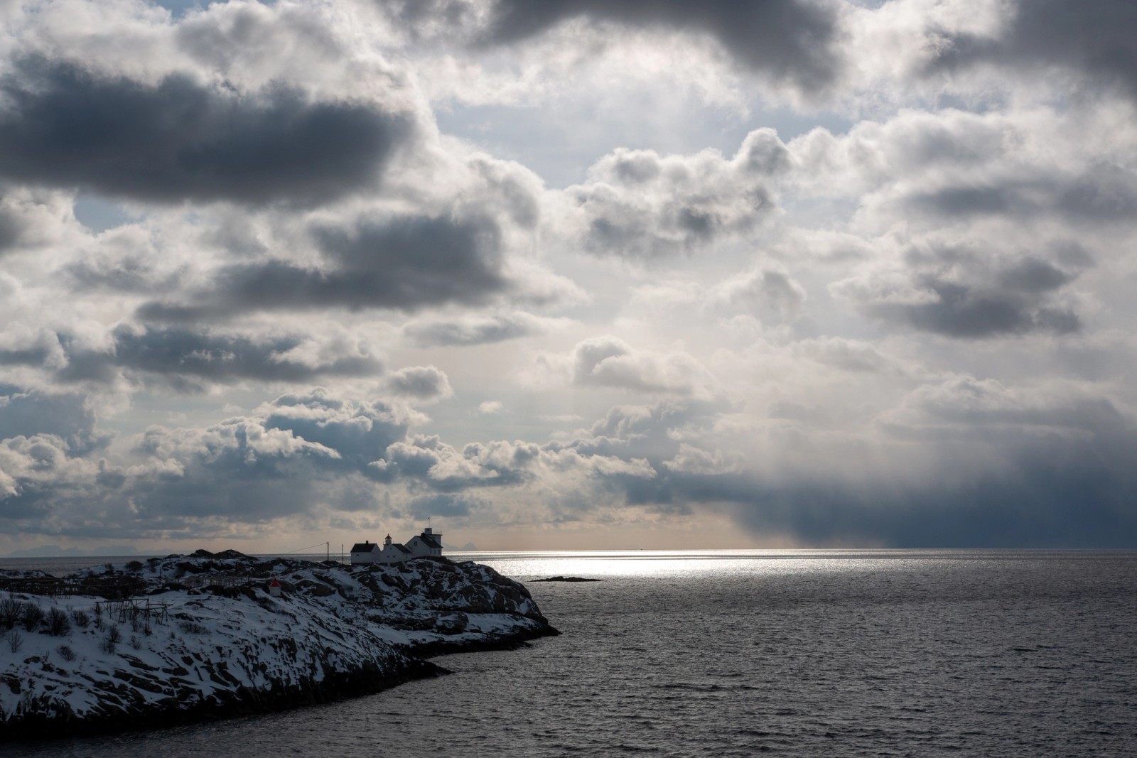 The lighthouse in Henningsvær, Stormy weather in the background with shimmers of sunshine