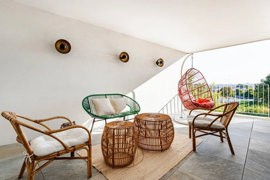 Salon extérieur de la loggia avec fauteuil suspendu et assises en rotin