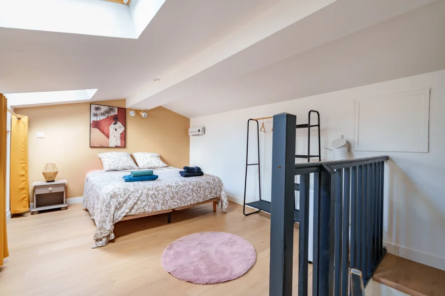 Vue d’ensemble de la chambre mansardée avec escalier du duplex