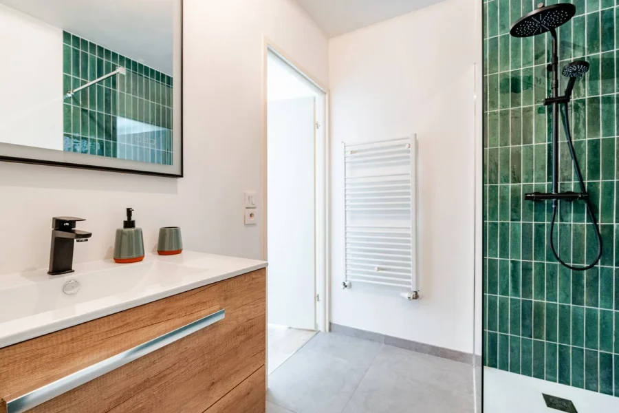 Salle de bain de L'Échappée : vasque, sèche-serviettes et douche en zellige vert