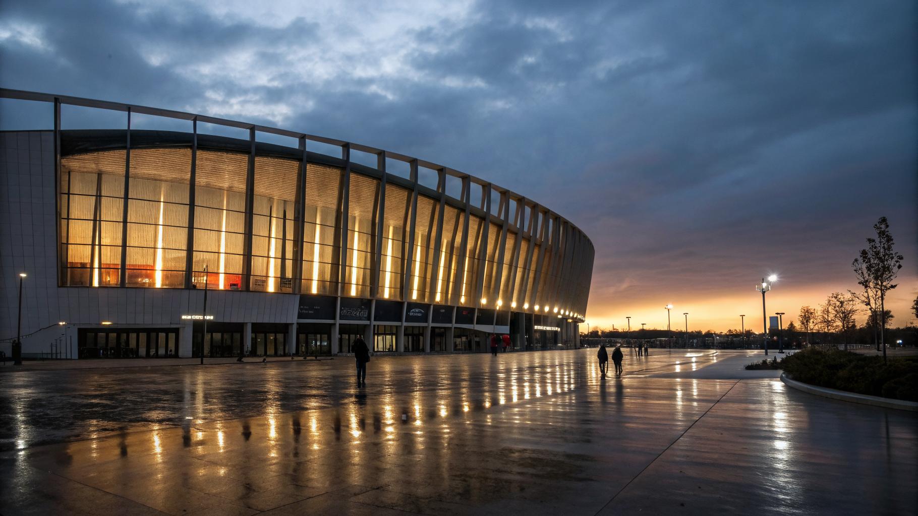 Arkéa Arena à Floirac au crépuscule, architecture contemporaine illuminée, reflets sur le sol mouillé, ciel entre chien et loup