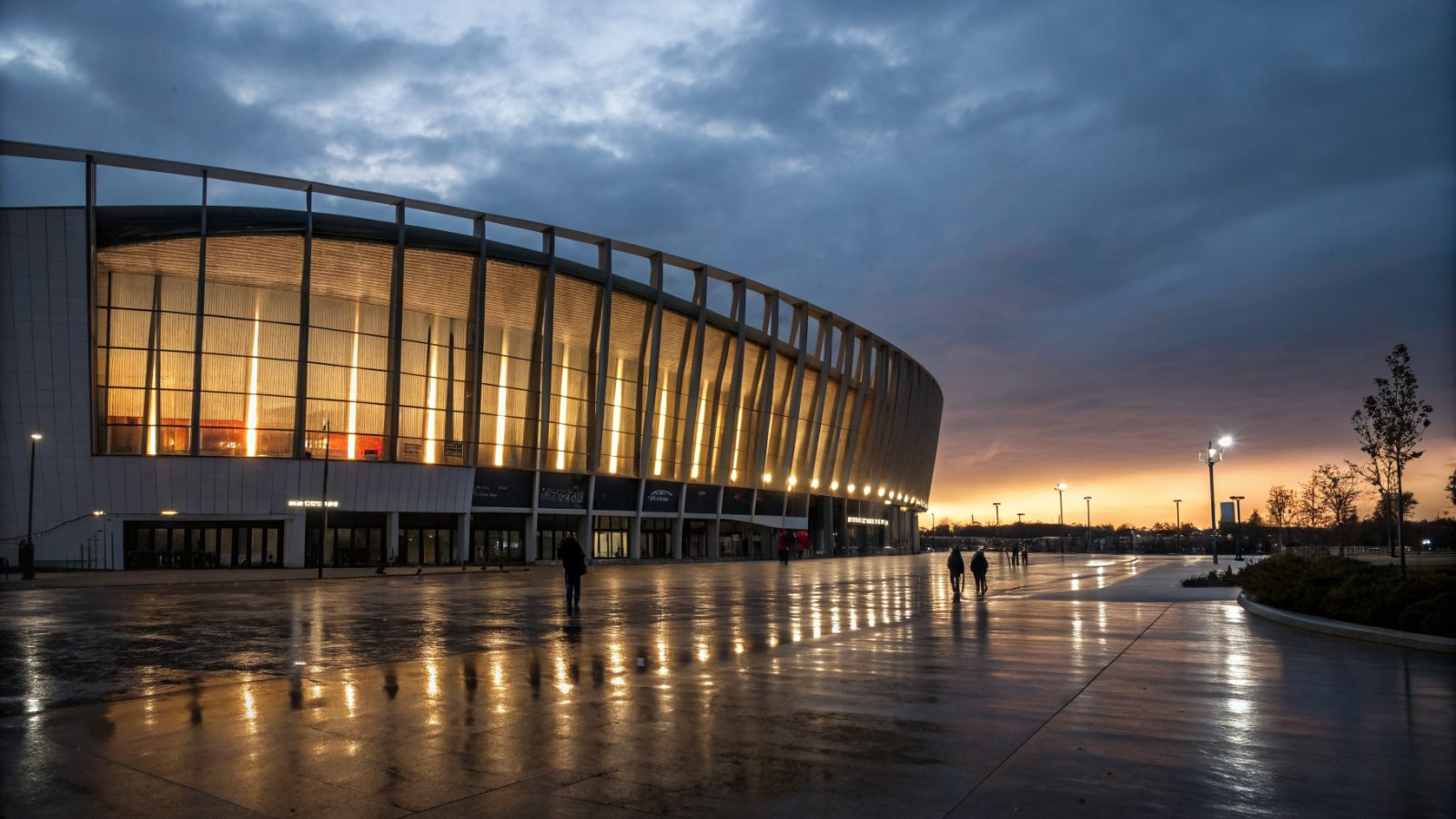Arkéa Arena à Floirac au crépuscule, architecture contemporaine illuminée, reflets sur le sol mouillé, ciel entre chien et loup