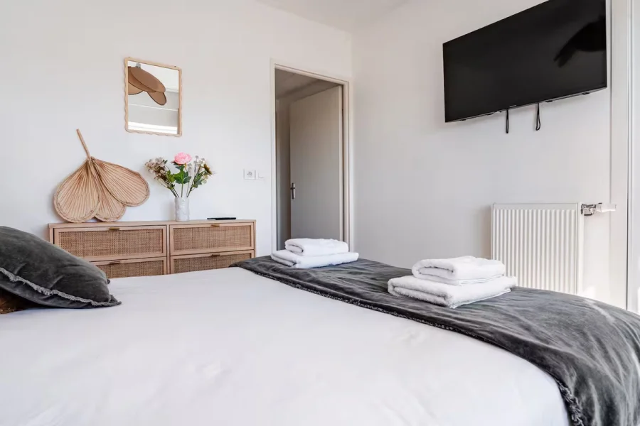 Chambre avec TV murale et serviettes préparées sur le lit
