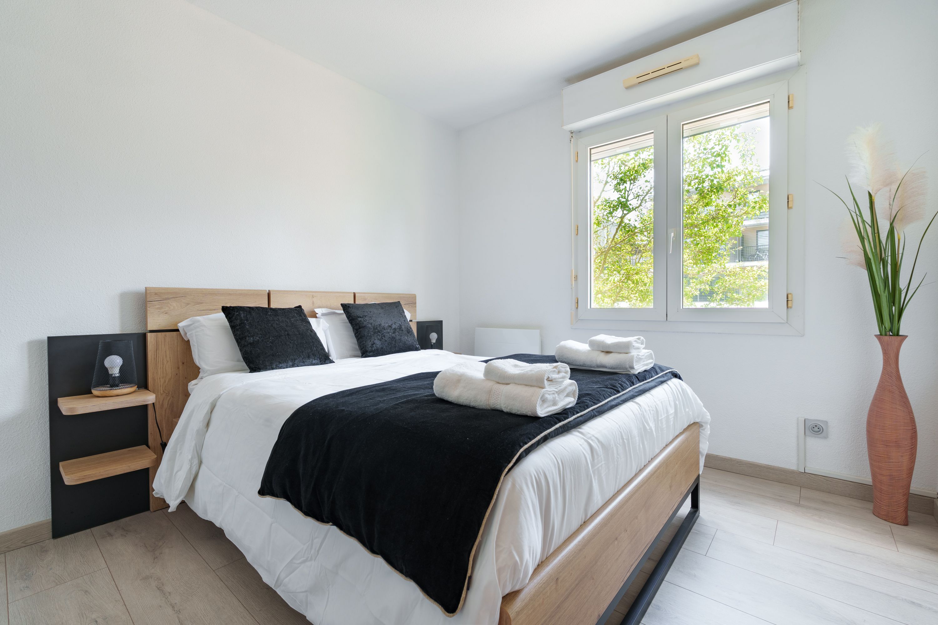 Chambre avec lit double, tête de lit en bois et serviettes préparées
