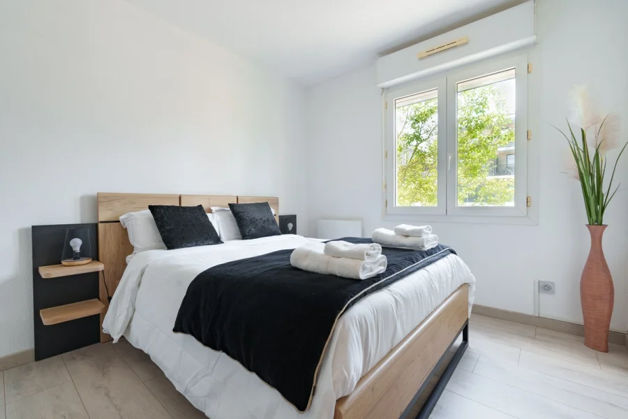 Chambre avec lit double, tête de lit en bois et serviettes préparées