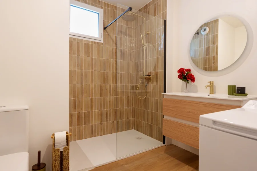 Salle de bain avec douche, meuble vasque en bois et WC
