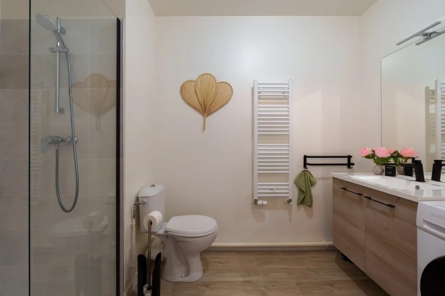 Salle de bain avec douche vitrée, sèche-serviettes et meuble vasque en bois