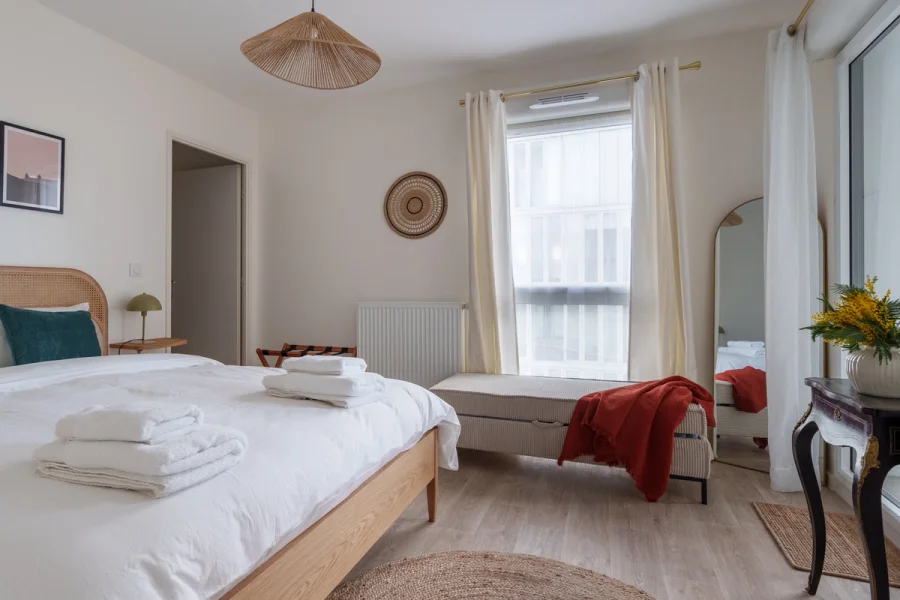 Chambre principale avec lit double, banc coffre et grand miroir arche