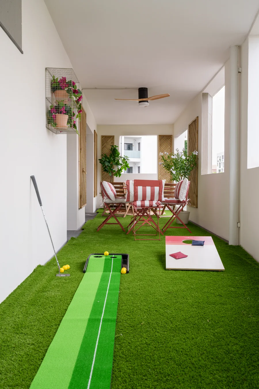 Terrasse avec putting green et jeu de cornhole sur gazon synthétique