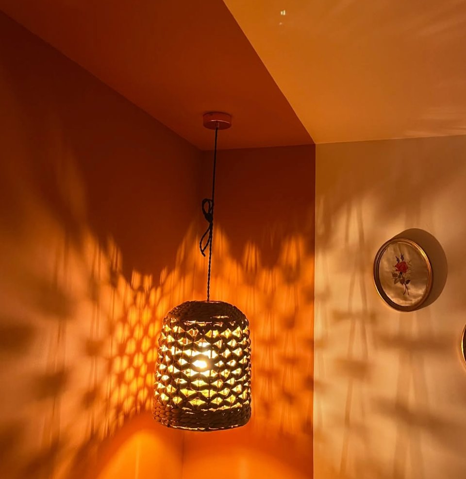 Suspension ajourée projetant des motifs de lumière sur un mur orangé