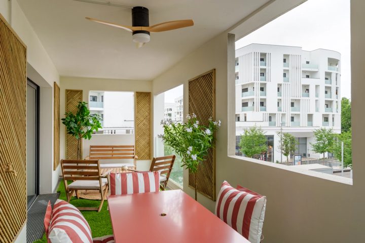 Terrasse de 25 m² de L'Esplanade avec table rouge et salon d'extérieur
