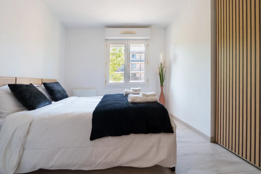 Chambre avec lit double, plaid bleu nuit et grand placard en tasseaux de bois
