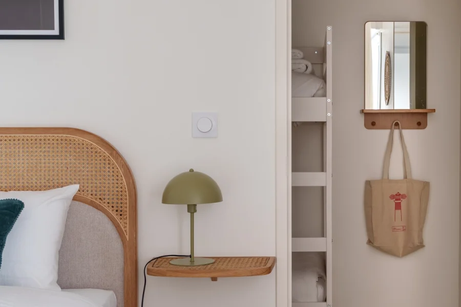 Détail de la tête de lit en cannage avec lampe de chevet verte