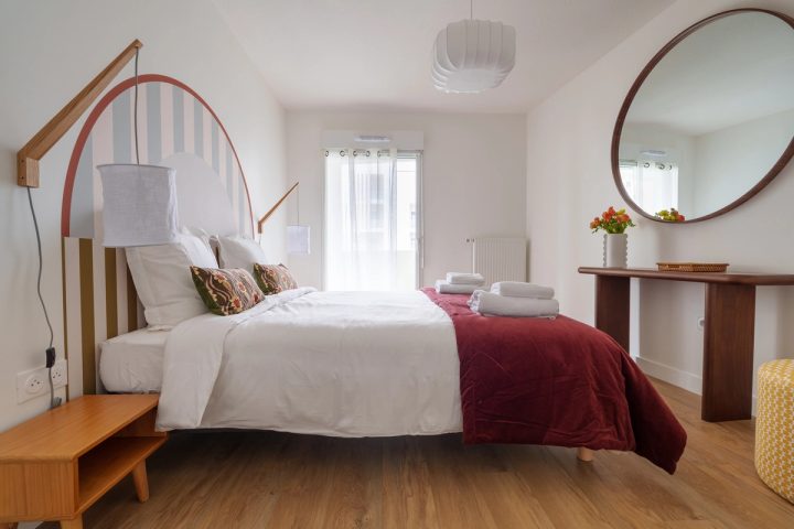 Seconde chambre avec tête de lit en arche et miroir rond