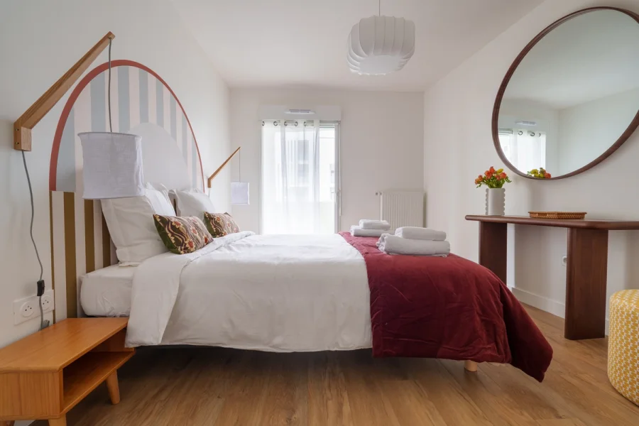 Seconde chambre avec tête de lit en arche et miroir rond