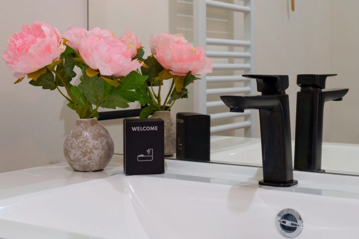 Détail de la vasque avec robinetterie noire, fleurs et kit de bienvenue
