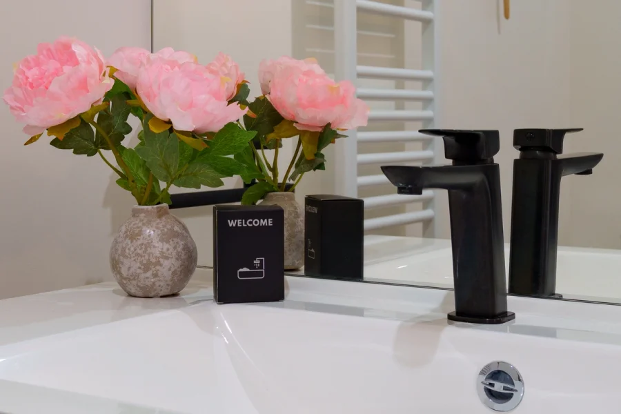 Détail de la vasque avec robinetterie noire, fleurs et kit de bienvenue