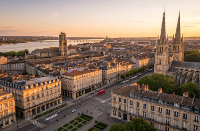Vue aérienne panoramique du centre historique de Bordeaux à l'heure dorée, toits en pierre calcaire et clochers d'église, Garonne en arrière-plan