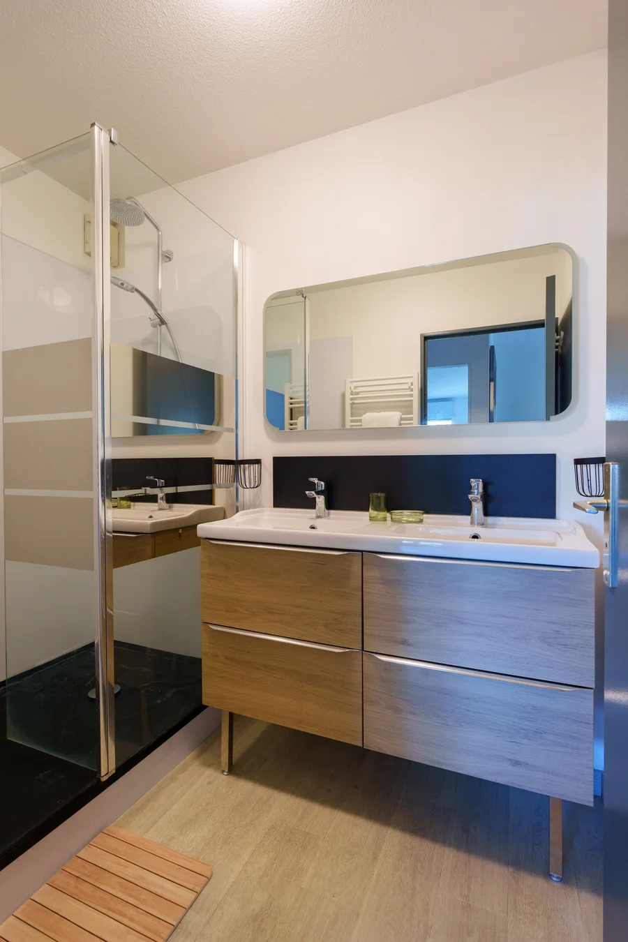 Salle de bain avec double vasque, grand miroir et douche spacieuse