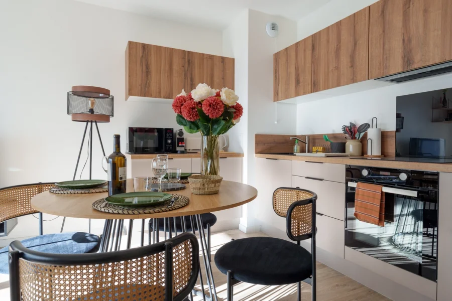 Cuisine équipée avec four, plan de travail en bois et table dressée