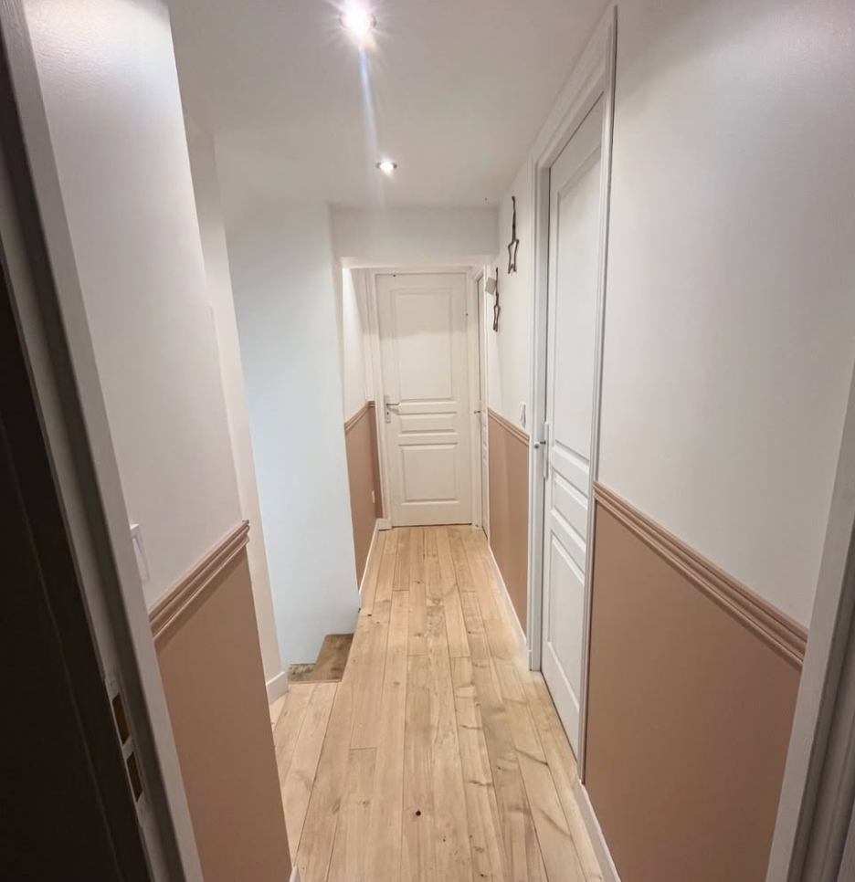 Couloir aux murs blancs et soubassement rose poudré, parquet clair