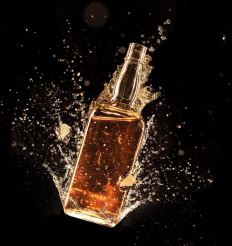 Gold coated bottle photographed in a liquid splash