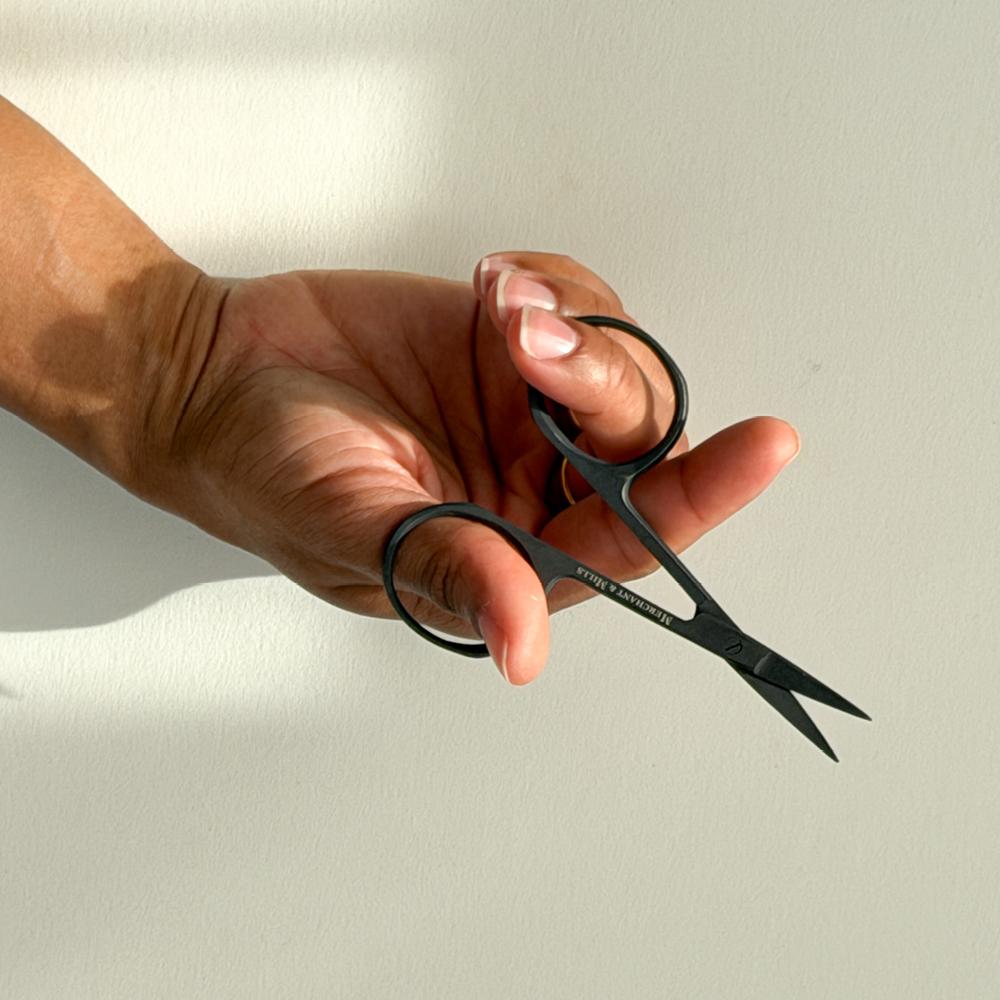 Ei hand held ei lita svart broderisaks framfor ein ljos bakgrunn