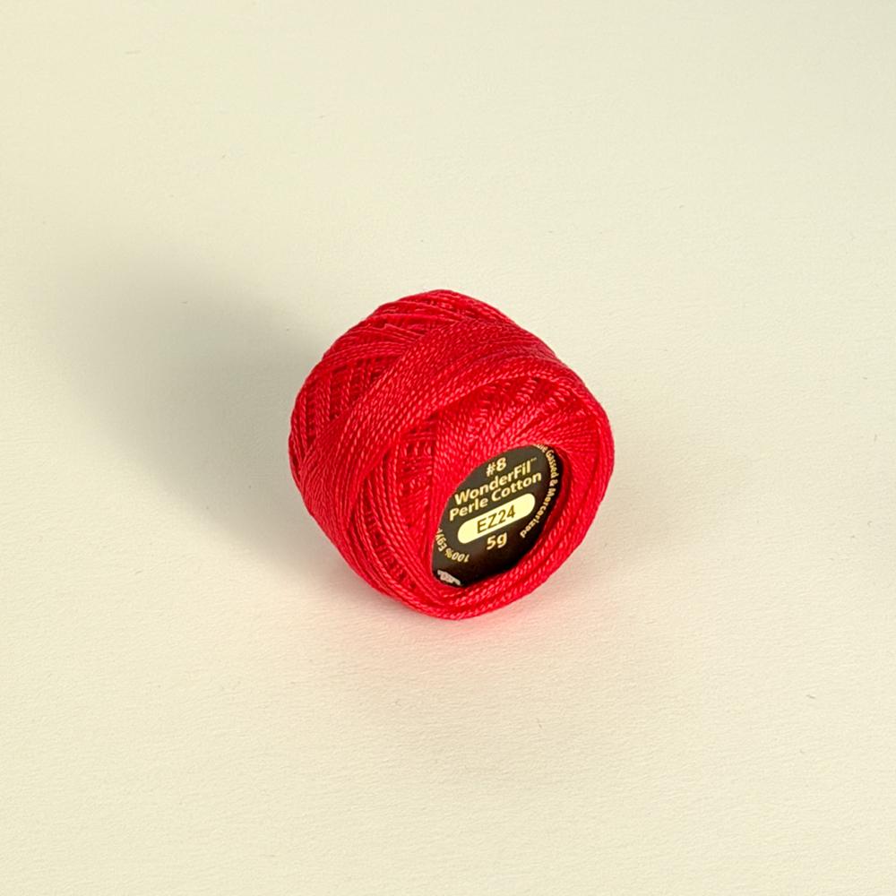 Ein raud spole med perlegarn i bomull på ein lys bakgrunn