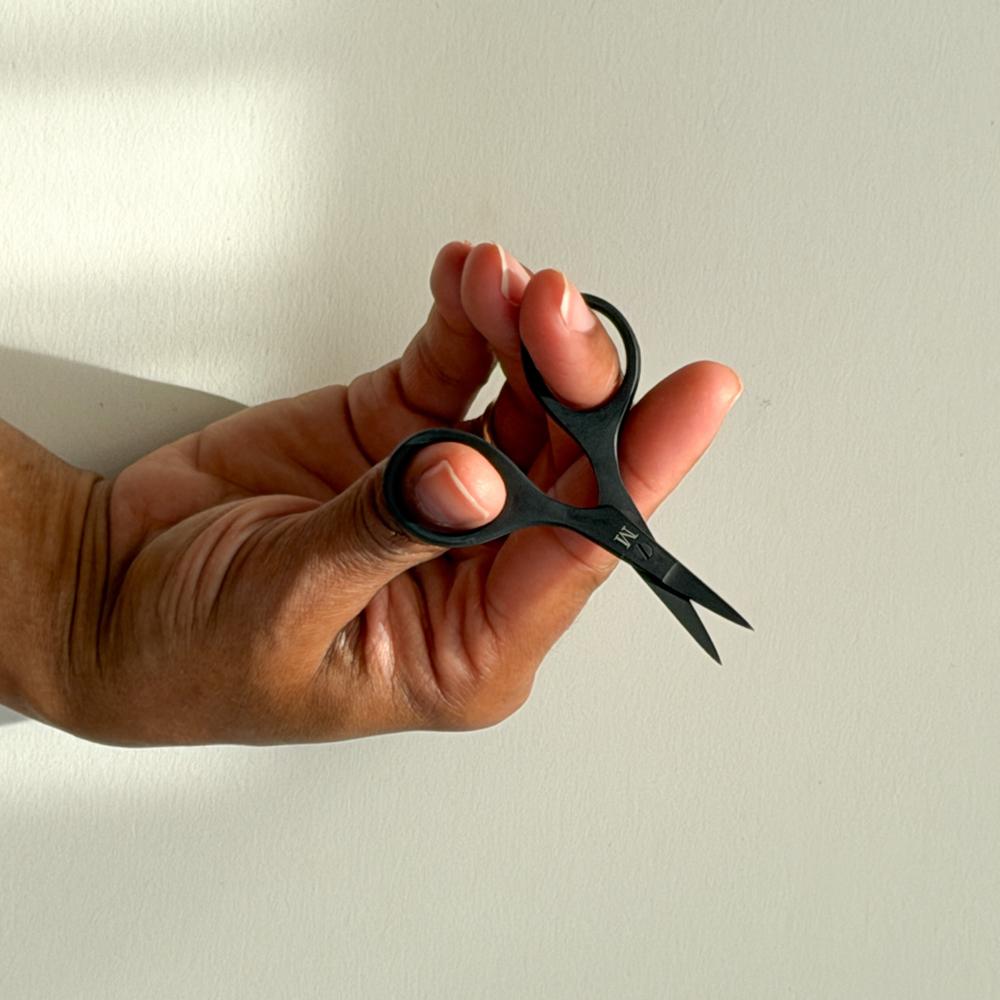 Ei hand held ei lita svart broderisaks framfor ein ljos bakgrunn