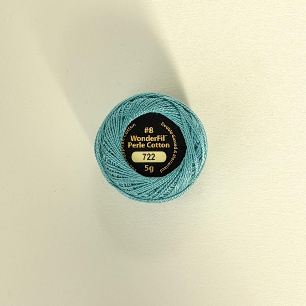 Ei hand held ei isblå garnnøste med ein etikett som viser nummer 716 og teksten WonderFil Perle Cotton