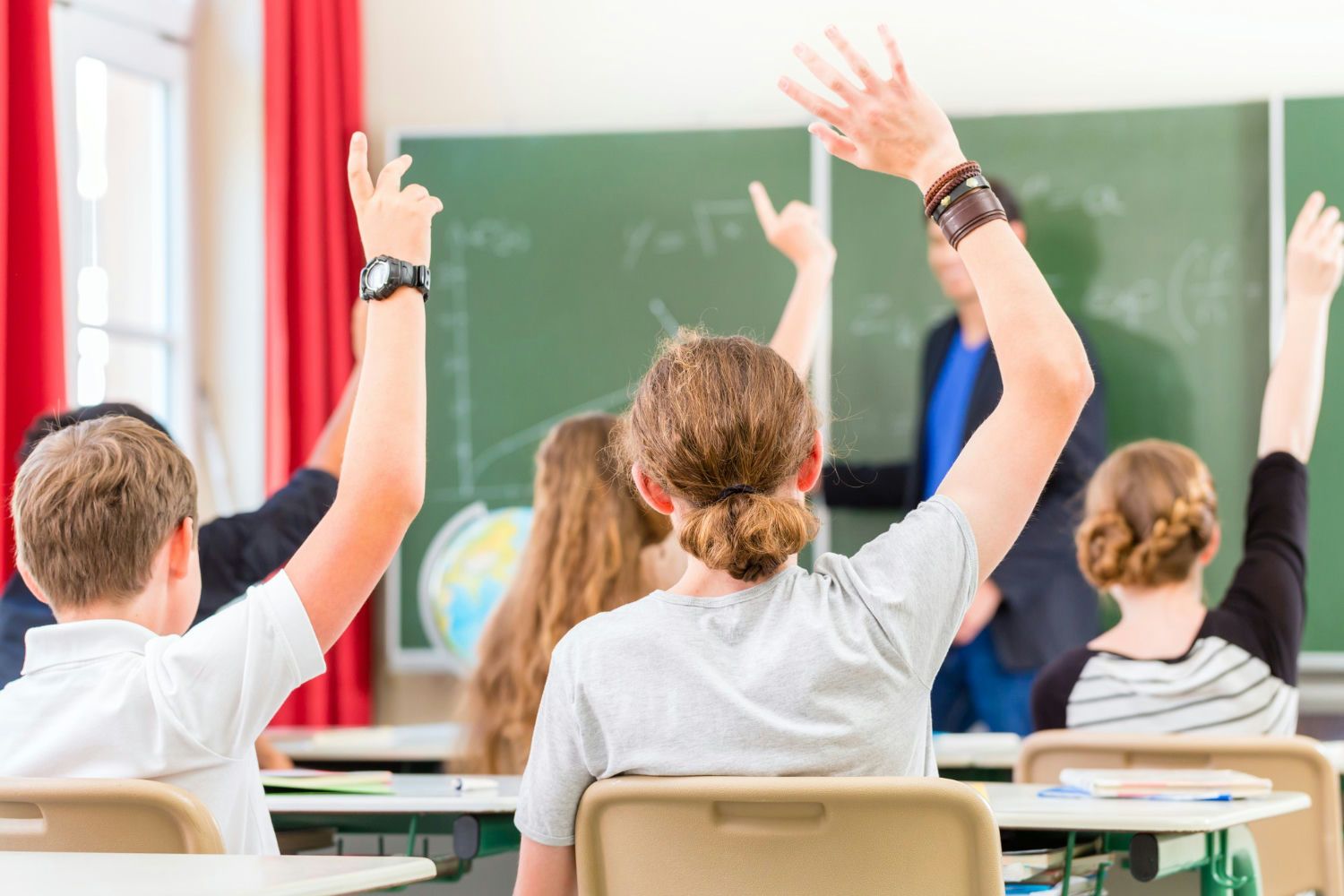Students raising hands in class
