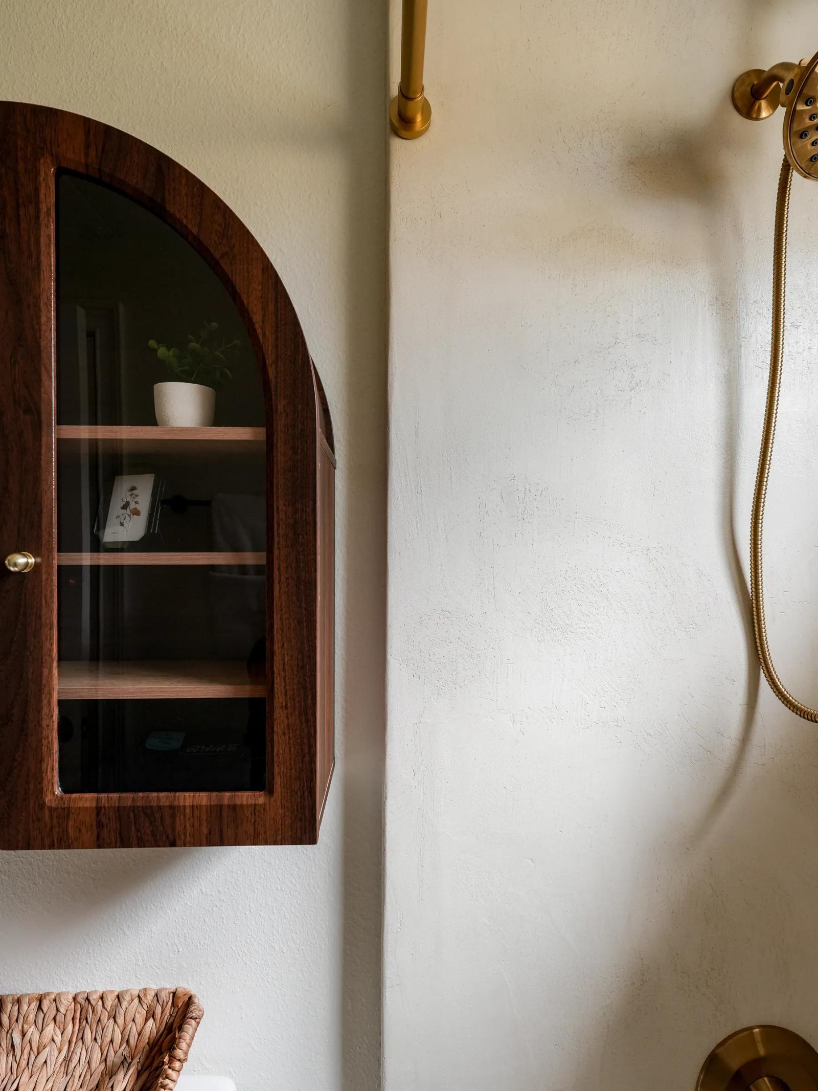 Close-up of the hand-troweled microcement wall texture beside the arched cabinet
