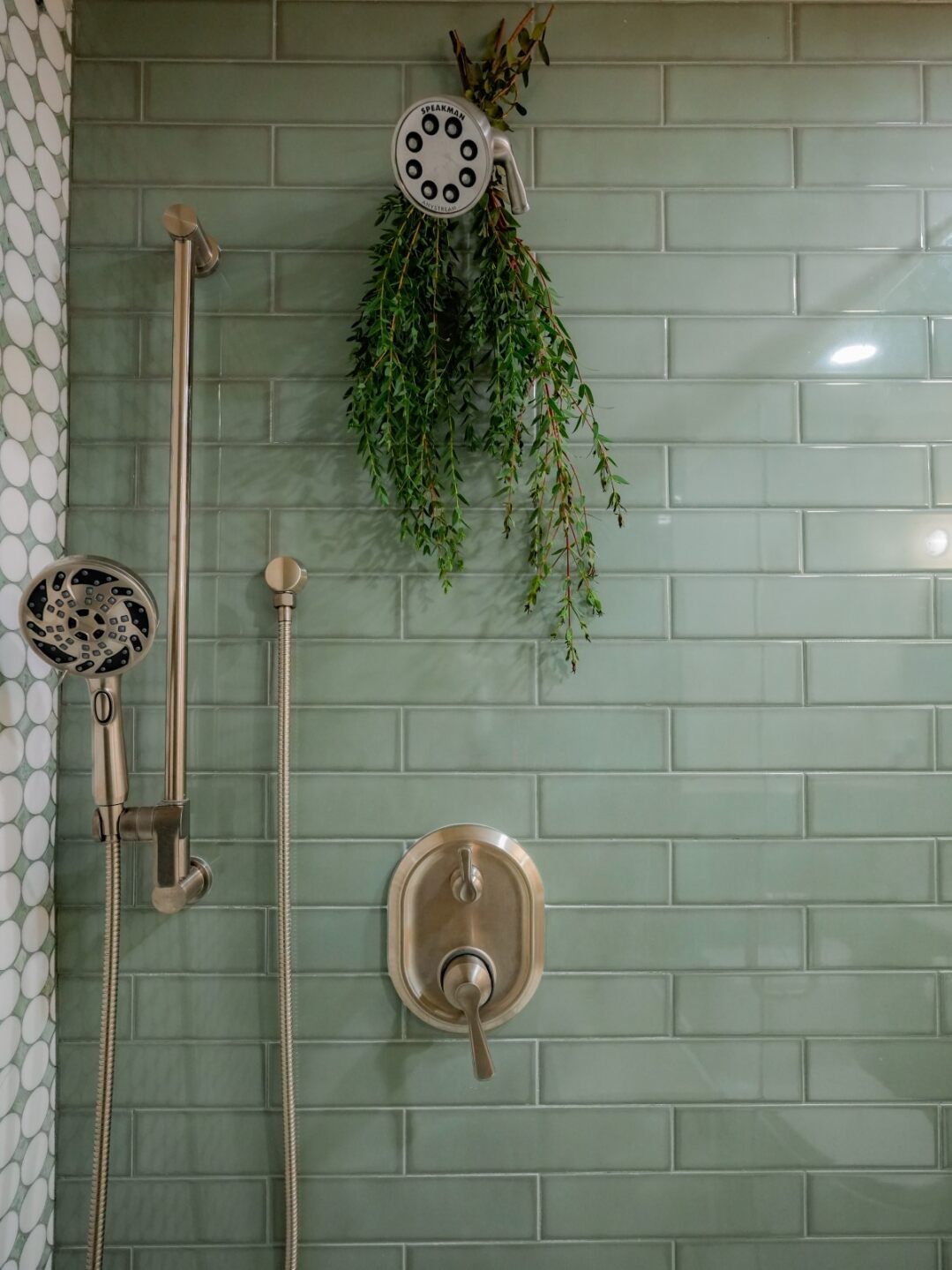 Green glazed-tile shower with brushed brass fixtures in a Ceballos bathroom remodel