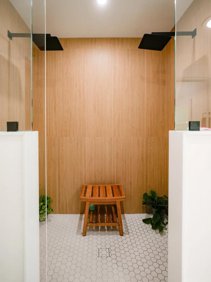 Walk-in shower with warm wood-look slat walls and a teak bench