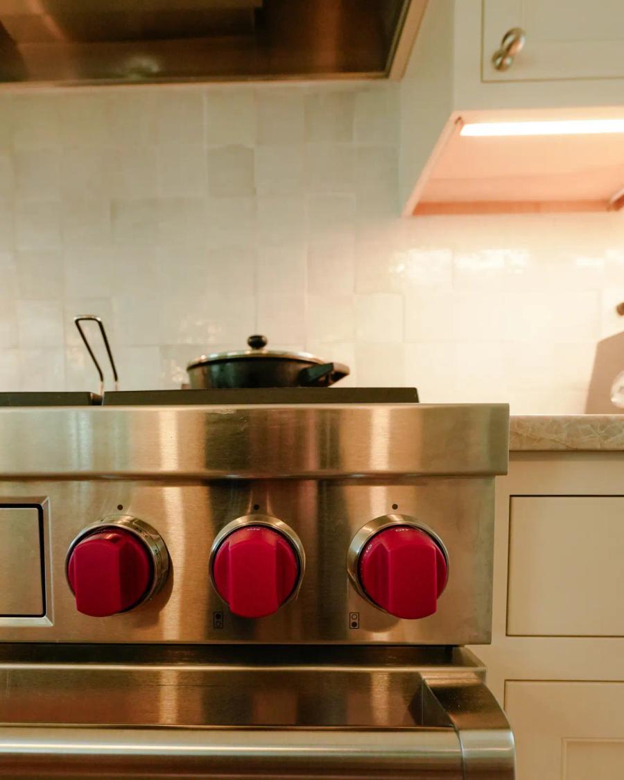 Professional range with red knobs set into white cabinetry